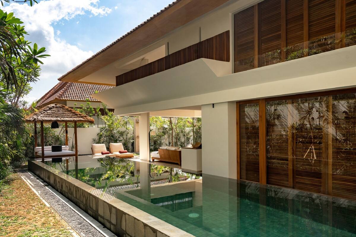 A modern house with a swimming pool, outdoor seating, and lush greenery.