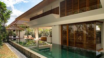 A modern house with a swimming pool, outdoor seating, and lush greenery.