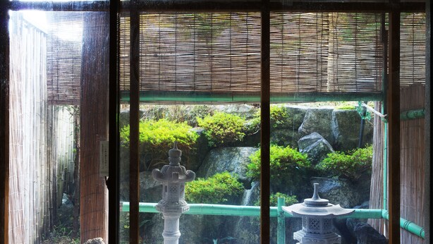 A traditional Japanese garden with stone lanterns and bamboo fencing. - Hotel Sanmalte (Hakuba)