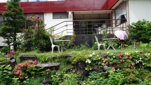 A building entrance with a red awning, stone steps, and white chairs. - Hotel Sanmalte (Hakuba)