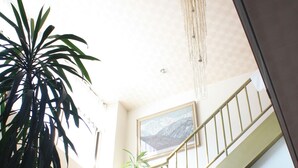 A staircase with a red carpet, a hanging light fixture, and a large window with a mountain view. - Hotel Sanmalte (Hakuba)