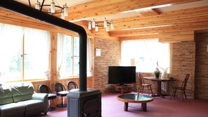 A cozy living room with a fireplace, a sofa, and a TV. - Hotel Sanmalte (Hakuba)