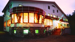 A two-story building with a stone foundation, multiple windows, and a staircase leading to a covered porch. - Hotel Sanmalte (Hakuba)