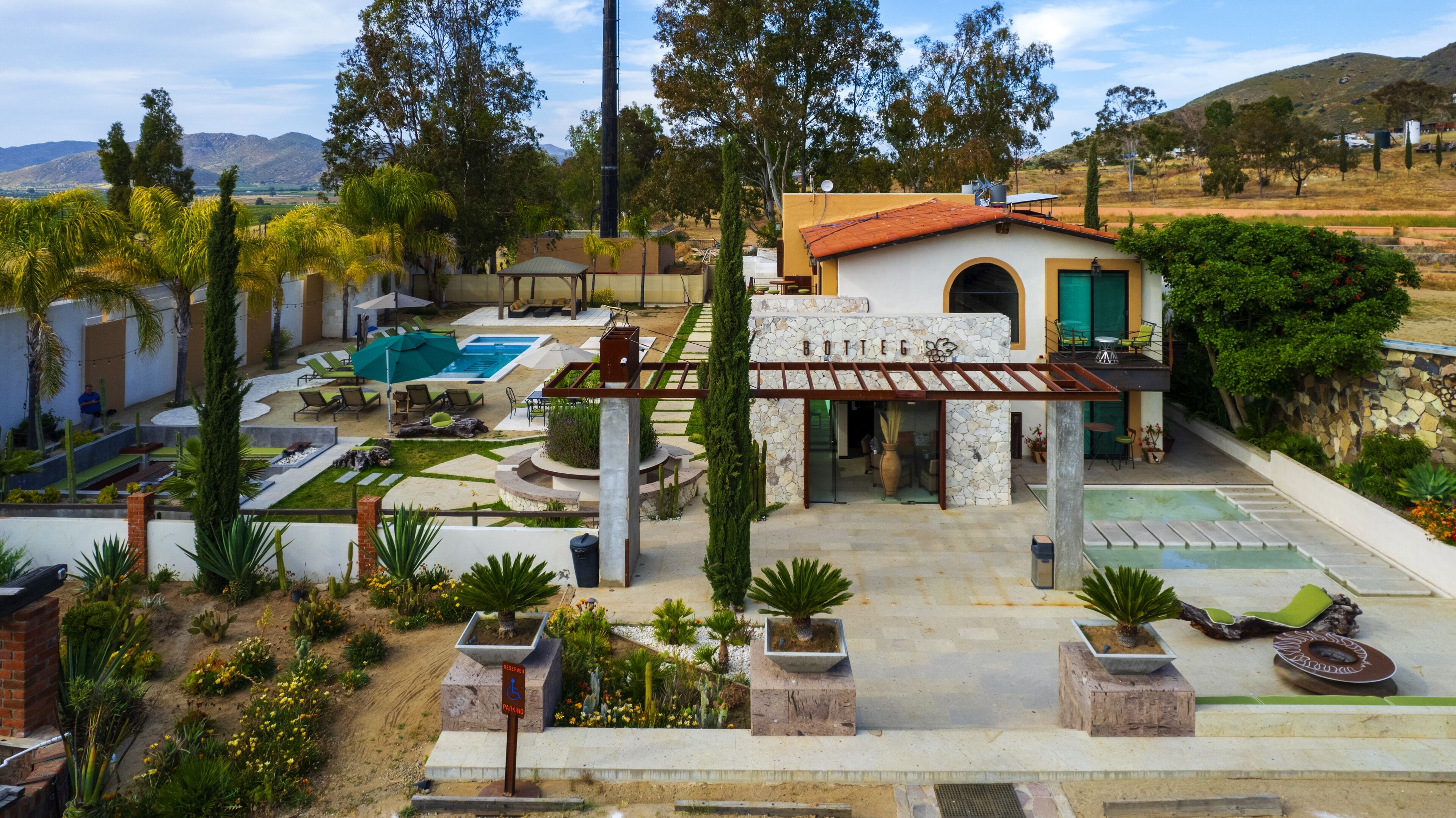 A resort with a swimming pool, outdoor seating, and a stone building with a green door.