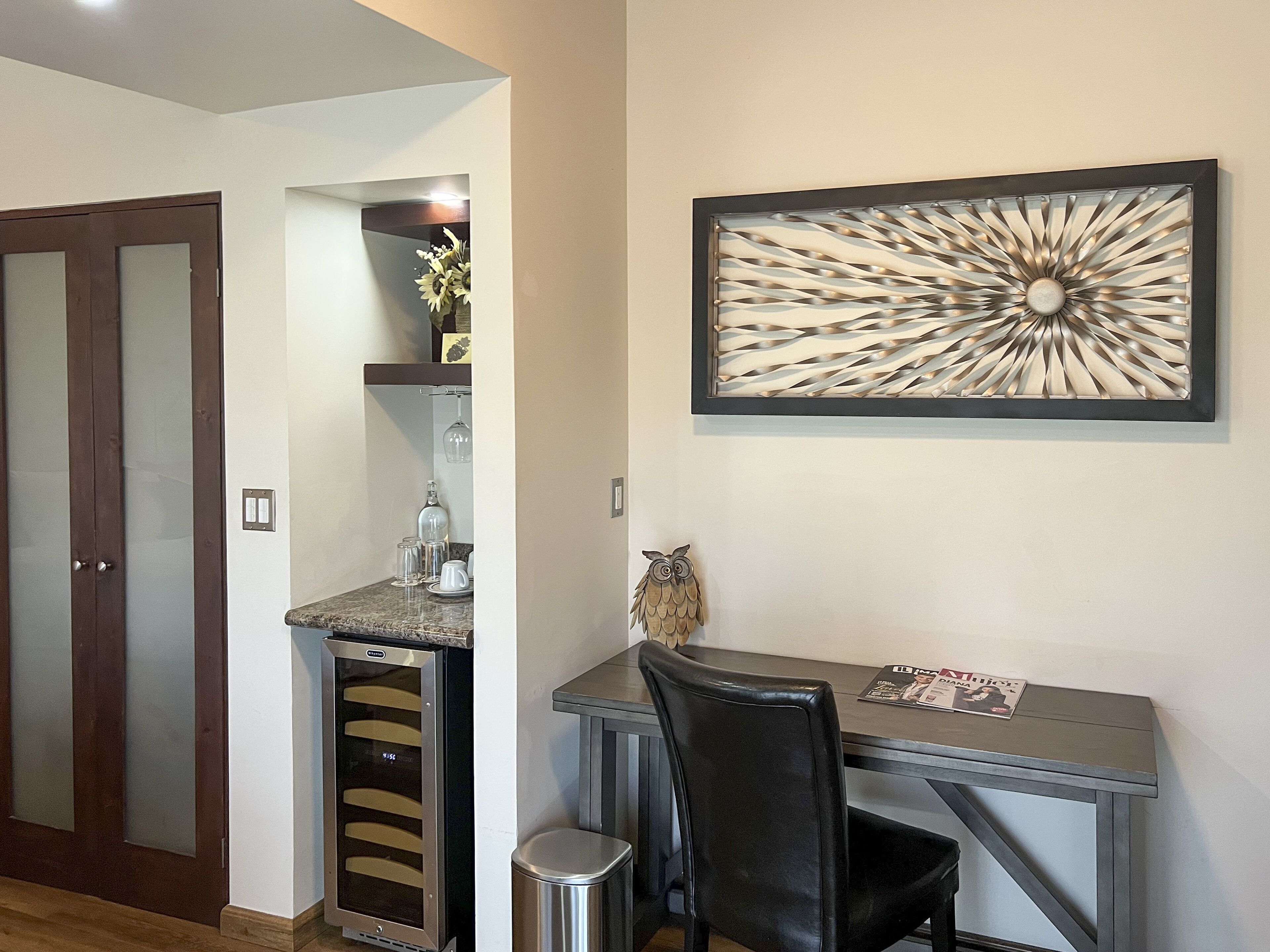 Una cocina moderna con horno empotrado, cafetera y comedor con mesa y sillas.