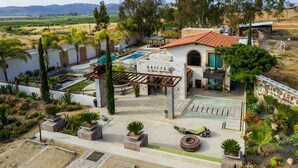 A hotel with a pool, outdoor seating, and a view of the surrounding landscape. - Bottega Hotel Boutique (Valle de Guadalupe)