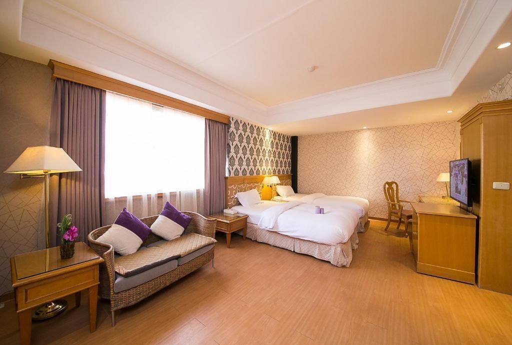 A hotel room with a bed, a sofa, a TV, and a desk.