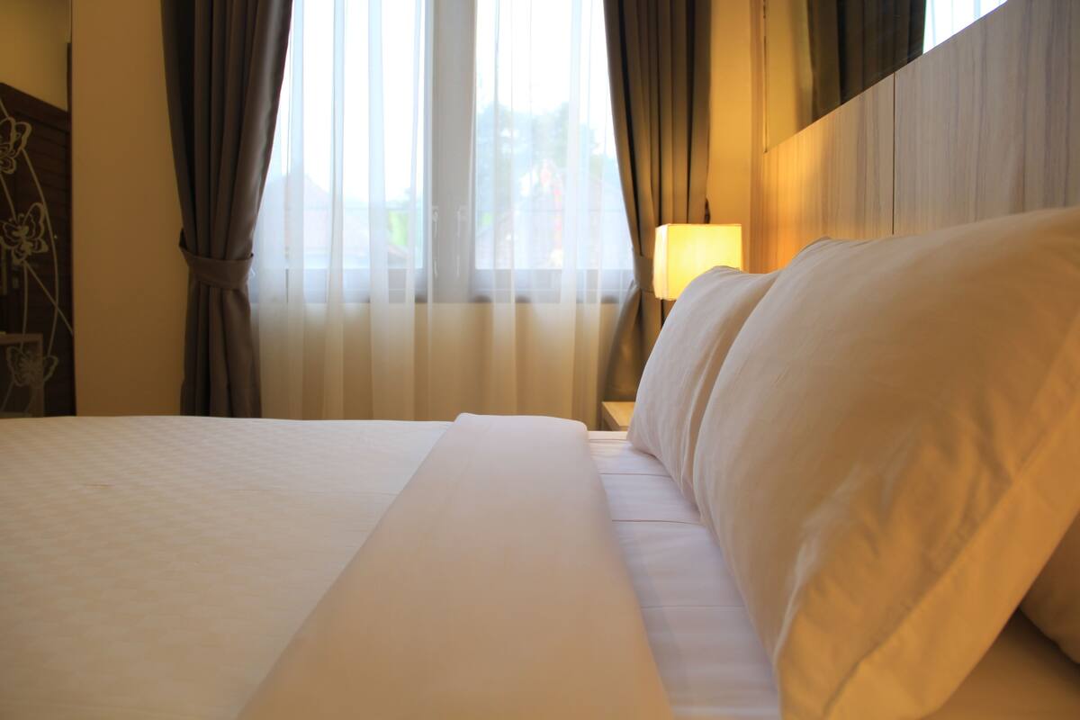 A neatly made bed with white linens in a hotel room.