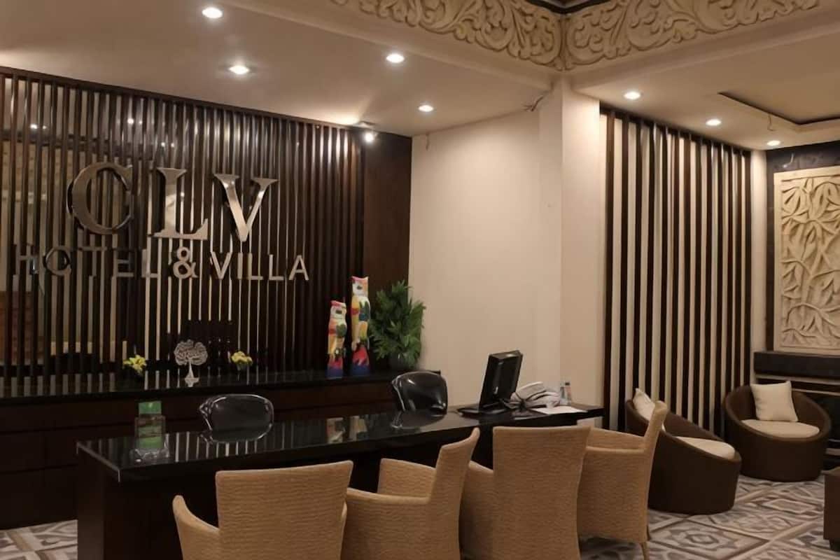 A reception area with a reception desk, chairs, and a wall with the hotel name.