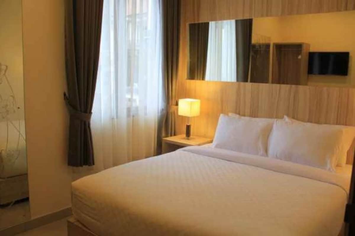 Una habitación de hotel con cama, mesita de noche, lámpara y televisión.