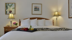 A neatly made bed with white linens, a tray of fruit and juice, and two bedside lamps. - Valley Star Motel (Penticton)