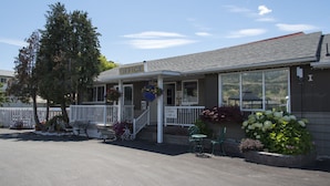 A building with a porch, a sign indicating coin laundry and ice, and a view of the surrounding area. - Valley Star Motel (Penticton)