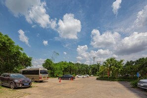 A parking area with a bus, cars, and a clear sky. - Xiangsihu International Hotel (Nanning)