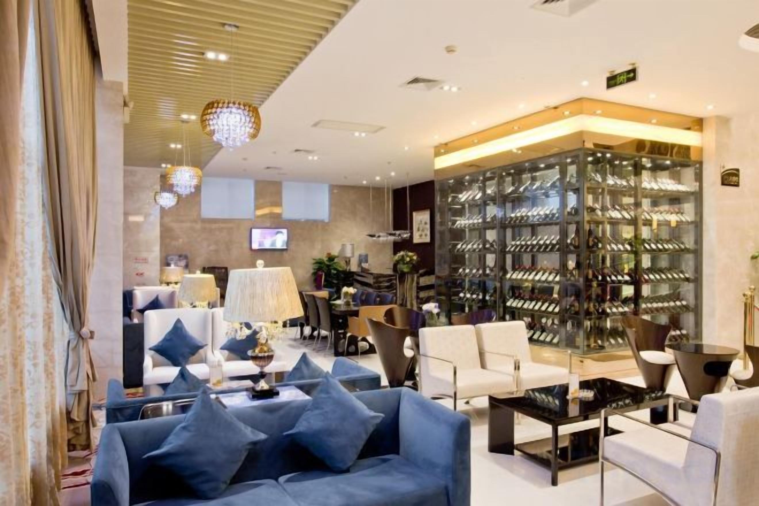 Un moderno vestíbulo de hotel con zona de estar, exhibición de vinos y televisión.