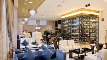 Un moderno vestíbulo de hotel con zona de estar, exhibición de vinos y televisión.