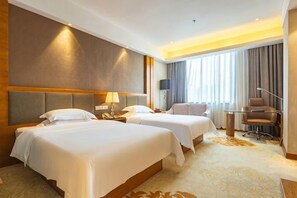 Une chambre d’hôtel avec deux lits, un bureau et une chaise.