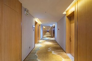 Een hotelgang met houten deuren en een vloerbedekking.