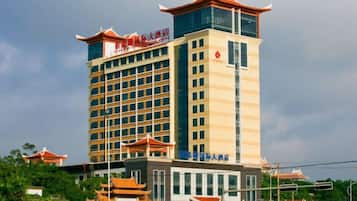 Un hotel de varios pisos con un estilo arquitectónico tradicional, que destaca por una torre prominente con tejado rojo y una señal que indica que es un hotel.