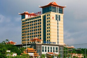 Un hotel de varios pisos con un estilo arquitectónico tradicional, que destaca por una torre prominente con tejado rojo y una señal que indica que es un hotel.