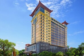 Een hotel met meerdere verdiepingen, met een traditioneel ontwerp, herkenbaar aan het opvallende rode dak en grote ramen.