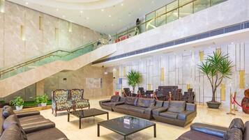 A spacious lobby with a high ceiling, a staircase, and a seating area with sofas and a coffee table.
