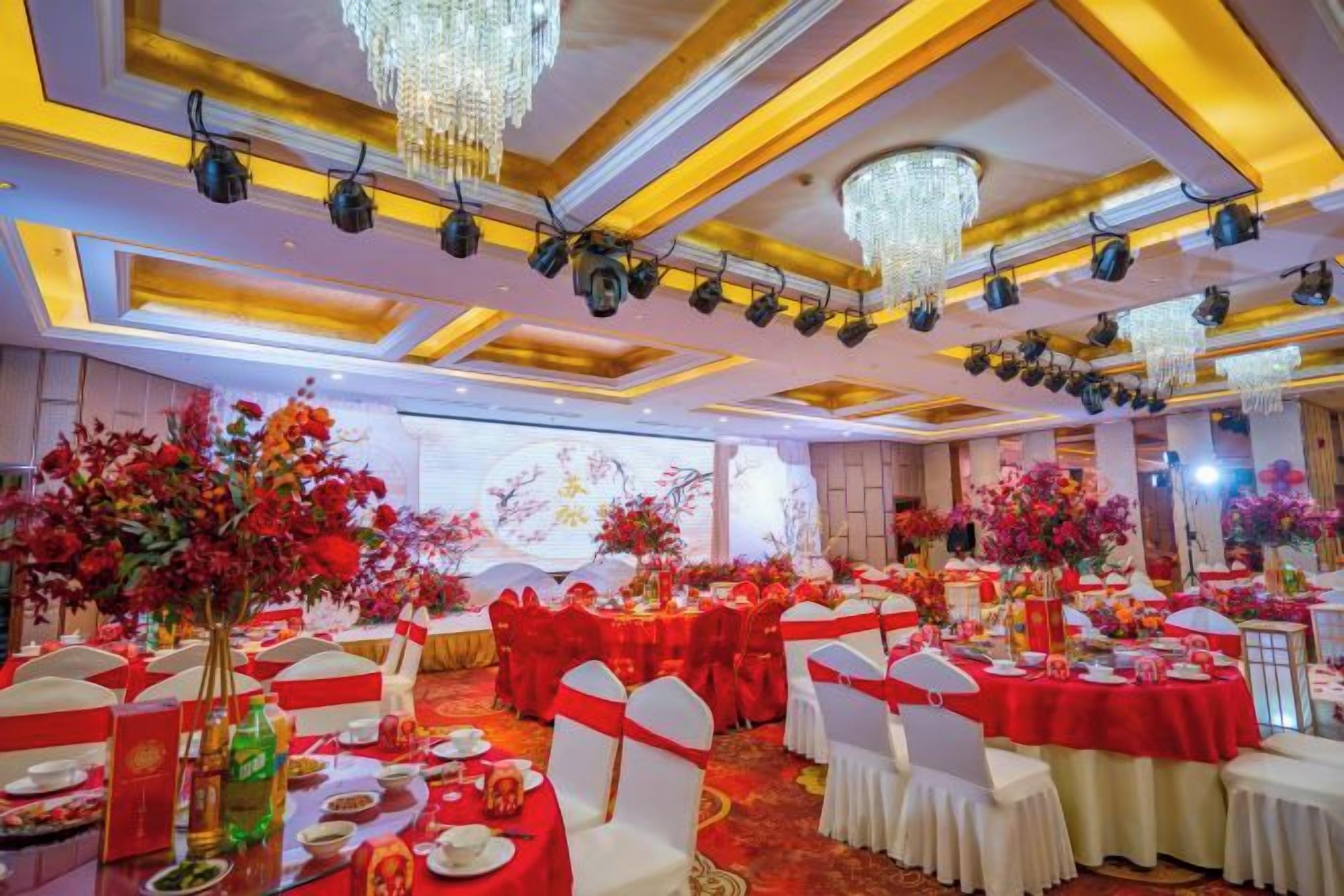 A banquet hall with round tables, chairs, and floral centerpieces.