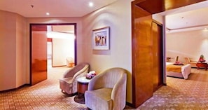A hotel room with a bed, a seating area with a chair and a small table, and a door leading to another room. - JI Hotel (Beijing 798 Art District) (Beijing)