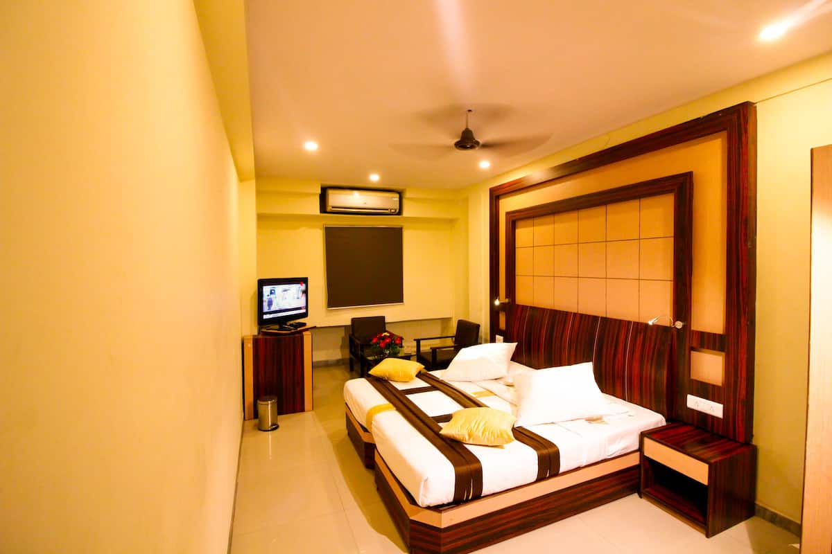 A hotel room with a large bed, a television, a desk, and a chair.