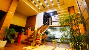 A modern interior with a staircase, wooden walls, and potted plants. - Hotel Rishi Regency (Jabalpur)