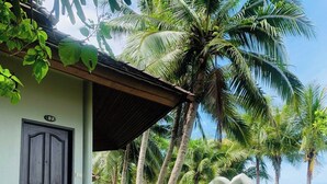 A resort with a covered porch, a sign reading 'KOCHANG,' and palm trees in the background. - Coral Resort (Ko Chang)