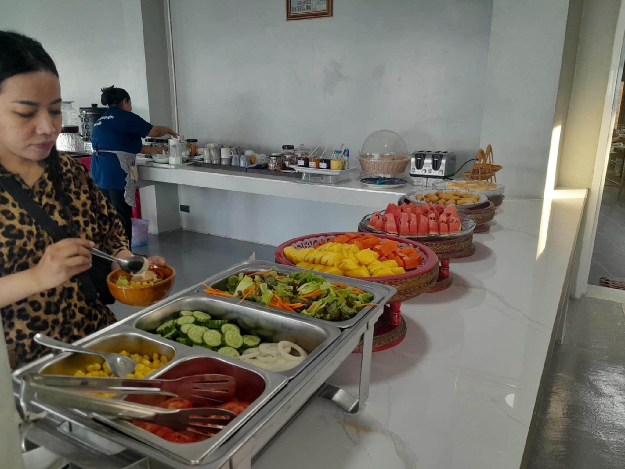 A buffet setup with various food items and a person serving themselves.