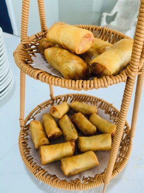 A three-tiered wicker basket filled with fried spring rolls. - Coral Resort (Ko Chang)