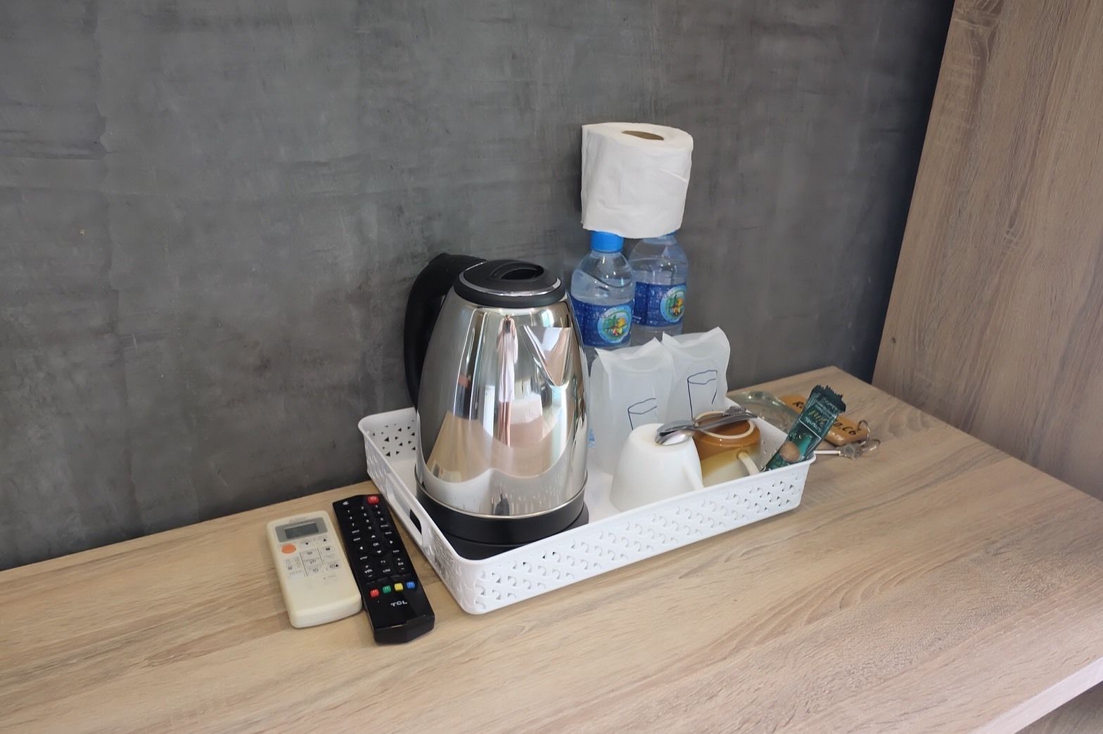 Eine Küchenarbeitsplatte mit Kaffeemaschine, Fernbedienung und Tablett mit Toilettenartikeln.