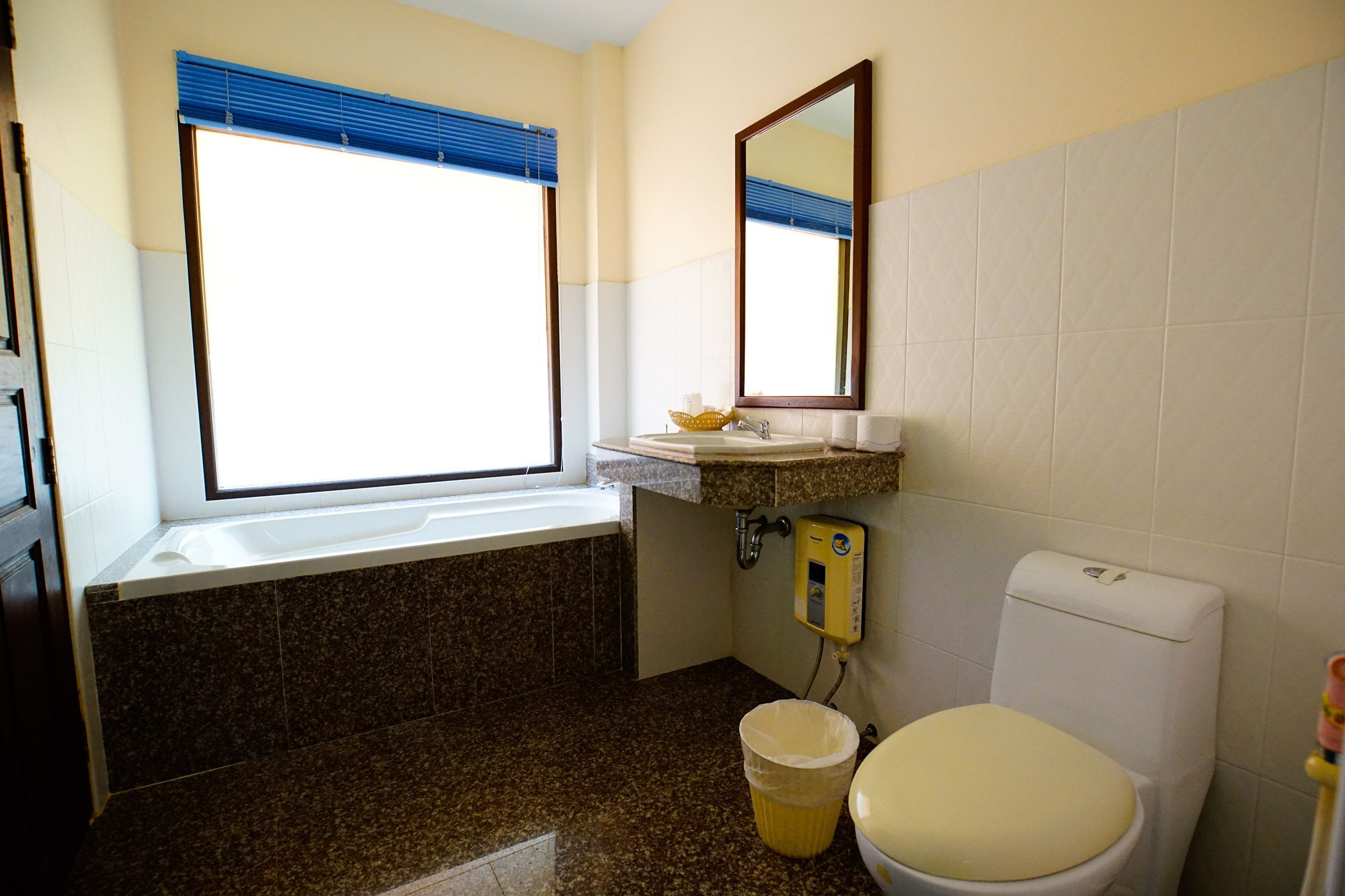 Et badeværelse med badekar, toilet, håndvask og et vindue.