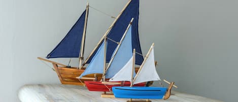 Three model sailboats on a wooden surface.