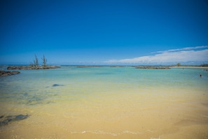 En la playa, playa de arena blanca, camastros y sombrillas