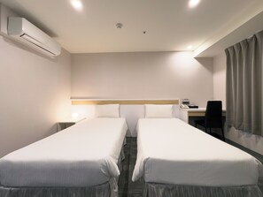 A hotel room with two single beds, a desk with a chair, a phone, and an air conditioning unit. - LUMOS INN (Taipei)