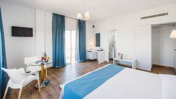 A hotel room with a bed, a desk, a chair, a TV, and a bathroom.