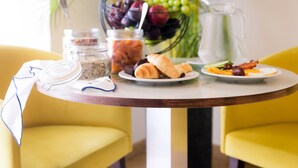 A dining table with breakfast items, a pitcher, and a plant in the background. - Mikes Kanarium Hotel (Larnaca)
