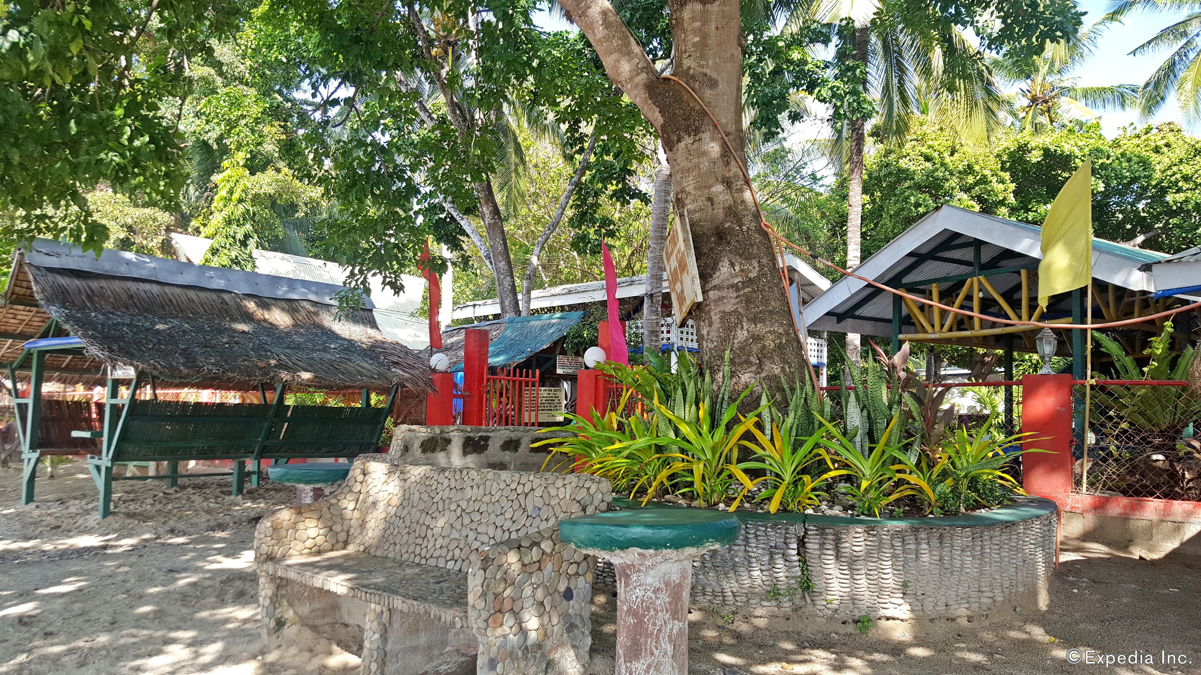 Un espace extérieur rustique aménagé avec des bancs en pierre et un petit élément décoratif aquatique.
