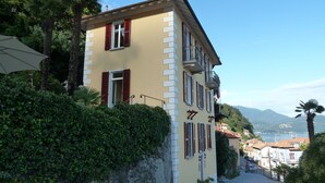 A building with a balcony, a stop sign, and a view of a town and mountains in the background. - B&B Casa Forster (Cannero Riviera)