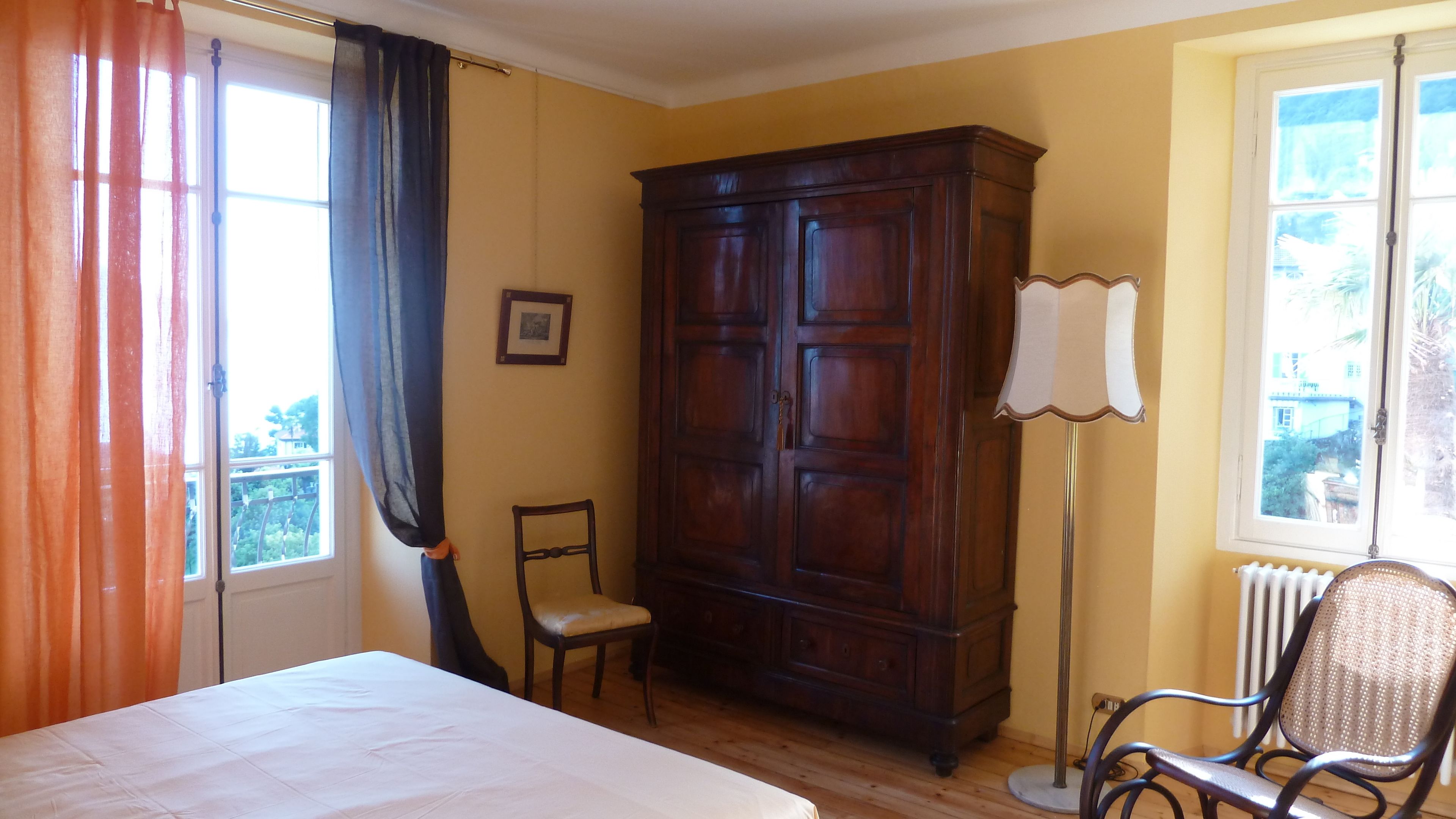 Une pièce comprenant un lit, une chaise, une armoire et un radiateur.