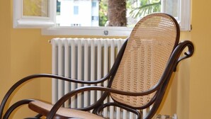A rocking chair in a room with a view of a mountain and palm tree outside a window. - B&B Casa Forster (Cannero Riviera)