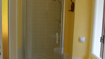 A bathroom with a glass-enclosed shower, a toilet, and a sink.