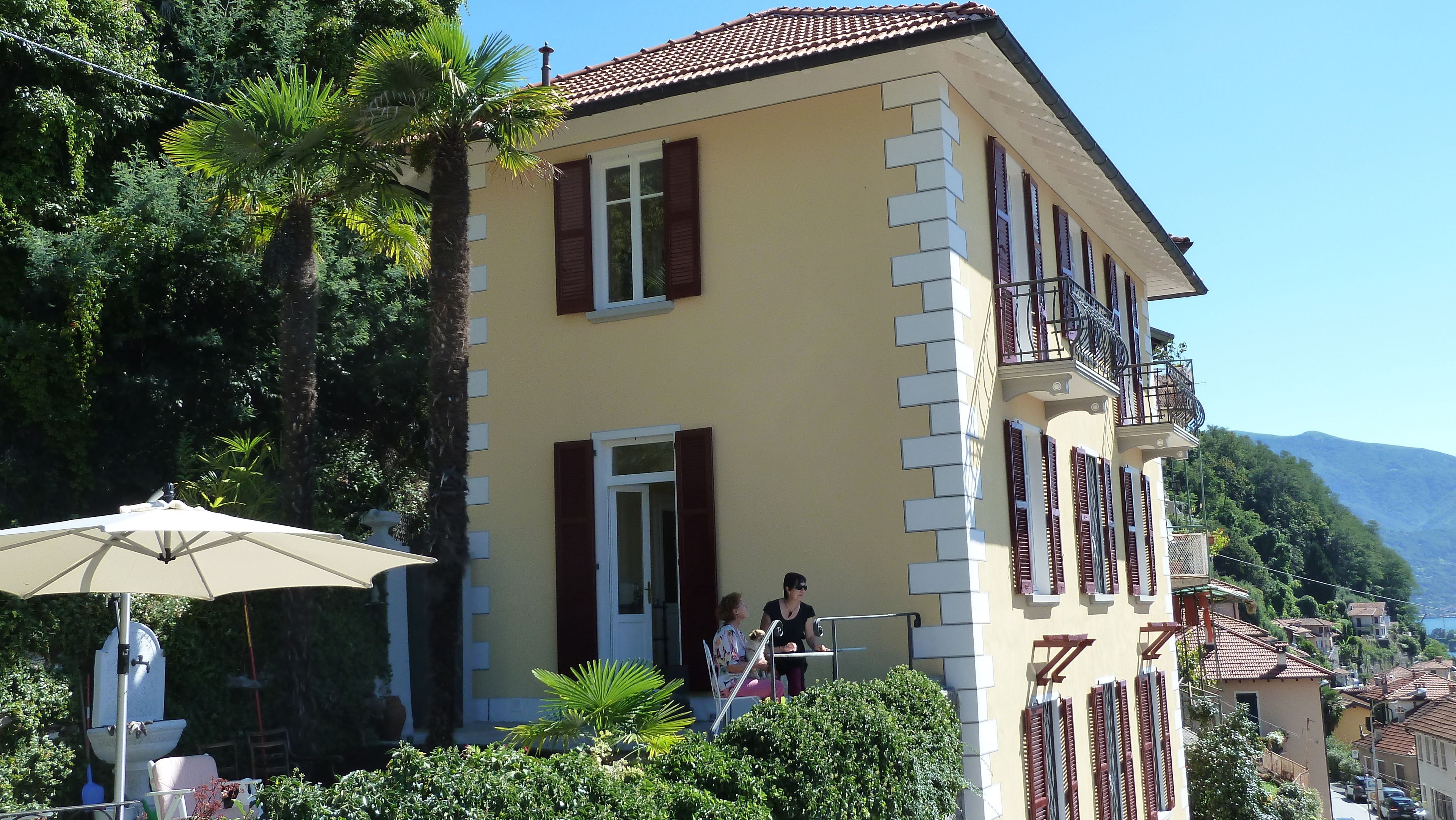 Ein gelbes Gebäude mit Balkon, Tür und Fenster mit Rollläden.