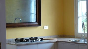 A kitchen with a gas stove, white cabinets, a window, and a mirror.
