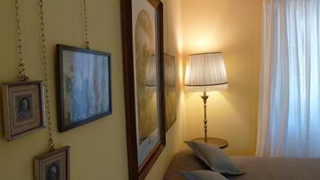 A bedroom with a bed, a lamp, and framed pictures on the wall.