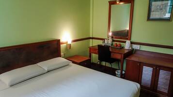 A hotel room with a bed, a desk, a chair, a mirror, and a nightstand.
