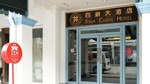 Het uiterlijk van het Four Chain Hotel met een duidelijke ingang, een bord met Zen Rooms en een zichtbaar voertuig ervoor.