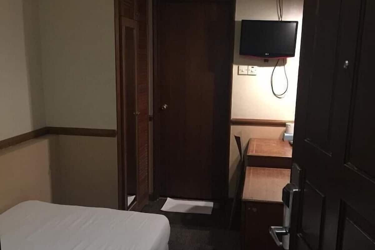 Una habitación de hotel con una cama, un escritorio, un televisor y un equipo de aire acondicionado.